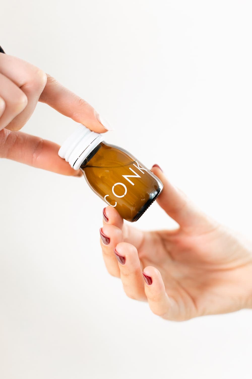 Two hands passing a CONKA bottle